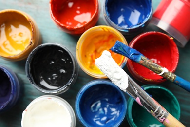 Photo of Jars with color paints and brushes on table, top view