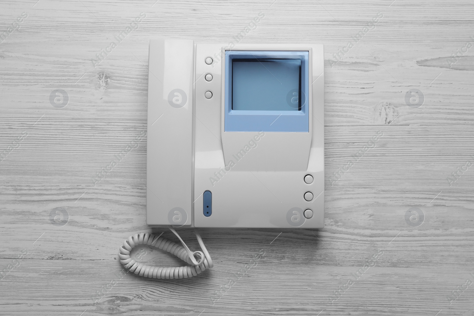 Photo of Modern intercom system with handset on white wooden background, top view