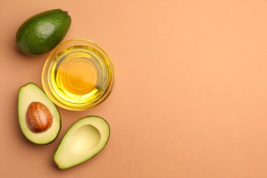 Photo of Cooking oil in bowl and fresh avocados on beige background, flat lay. Space for text