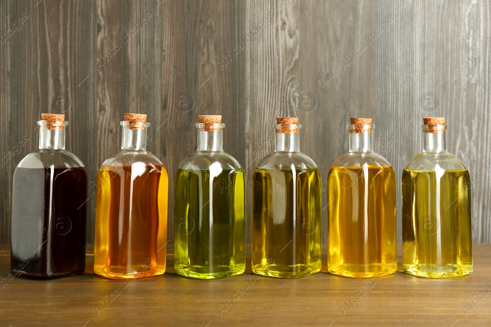 Photo of Vegetable fats. Different oils in glass bottles on wooden table