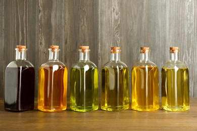 Photo of Vegetable fats. Different oils in glass bottles on wooden table
