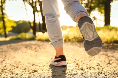Photo of Woman running on pathway outdoors in morning, closeup