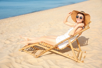 Photo of Young woman relaxing in deck chair on sandy beach