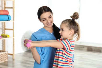 Orthopedist working with little girl in hospital gym