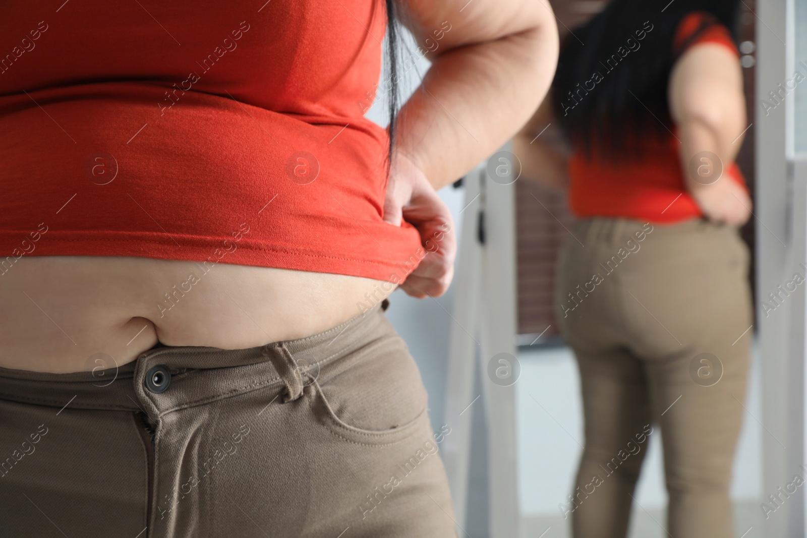 Photo of Overweight woman in tight shirt and trousers at home, closeup