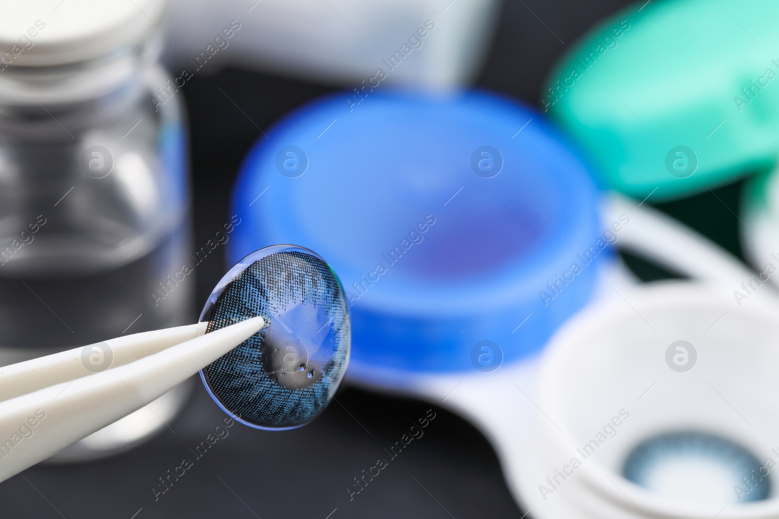 Photo of Tweezers with color contact lens over table, closeup. Space for text