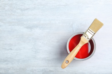 Photo of Can with red paint and brush on light background, top view. Space for text