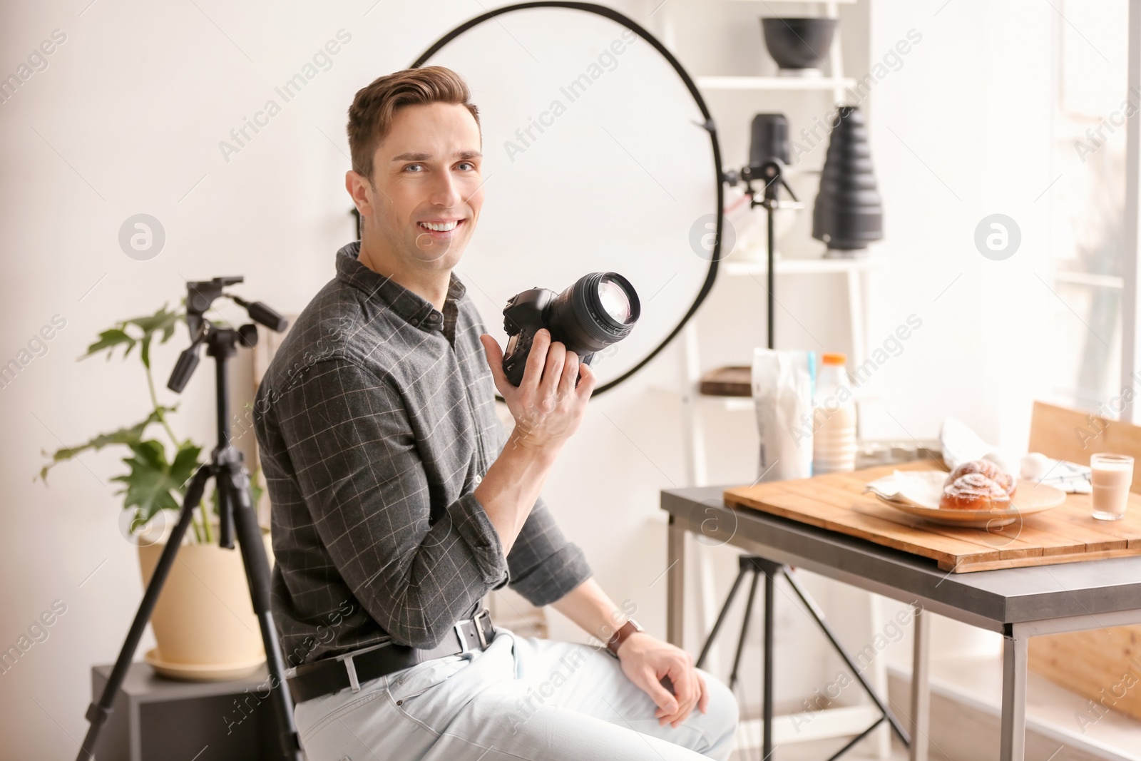 Photo of Young man with professional camera in photo studio