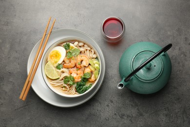 Delicious ramen with shrimps and egg in bowl served on grey table, flat lay. Noodle soup