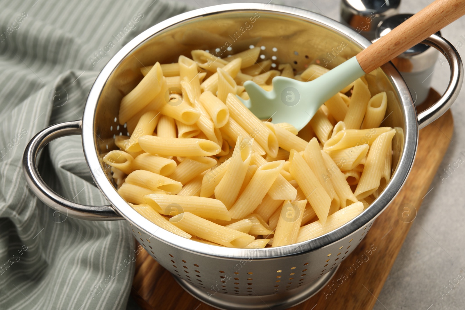 Photo of Delicious penne pasta in colander on table, closeup