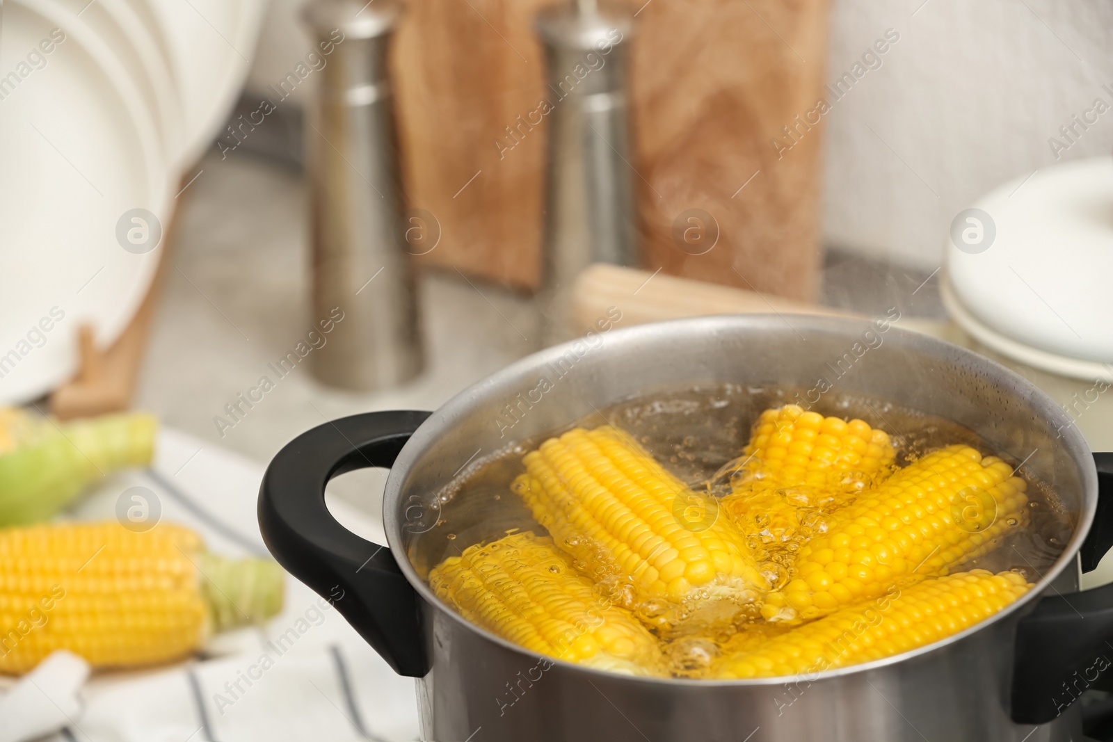 Photo of Stewpot with boiling water and corn cobs, closeup