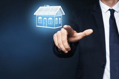 Image of Real estate agent touching house illustration on virtual screen against dark background, closeup