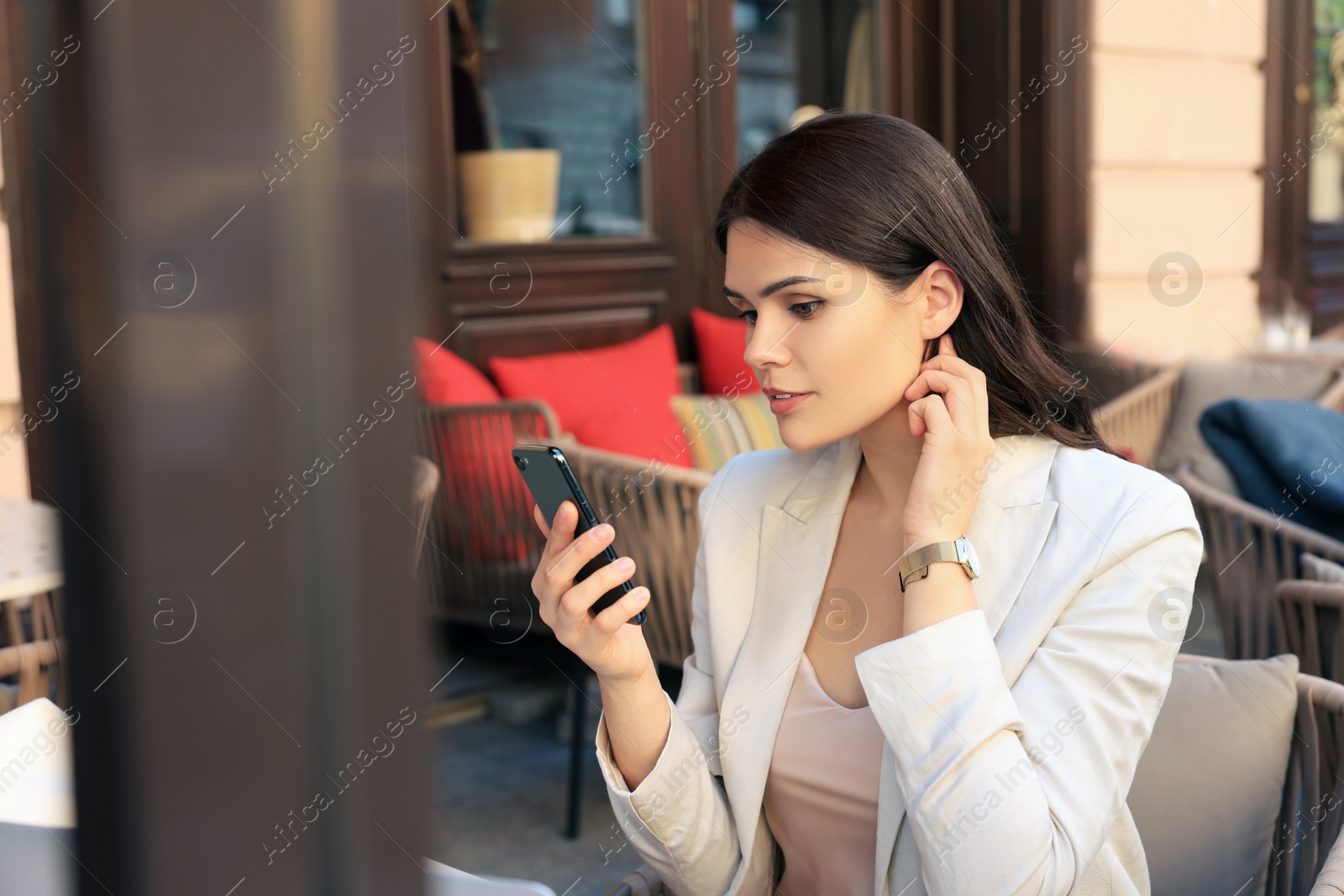 Photo of Beautiful young woman using smartphone in outdoor cafe