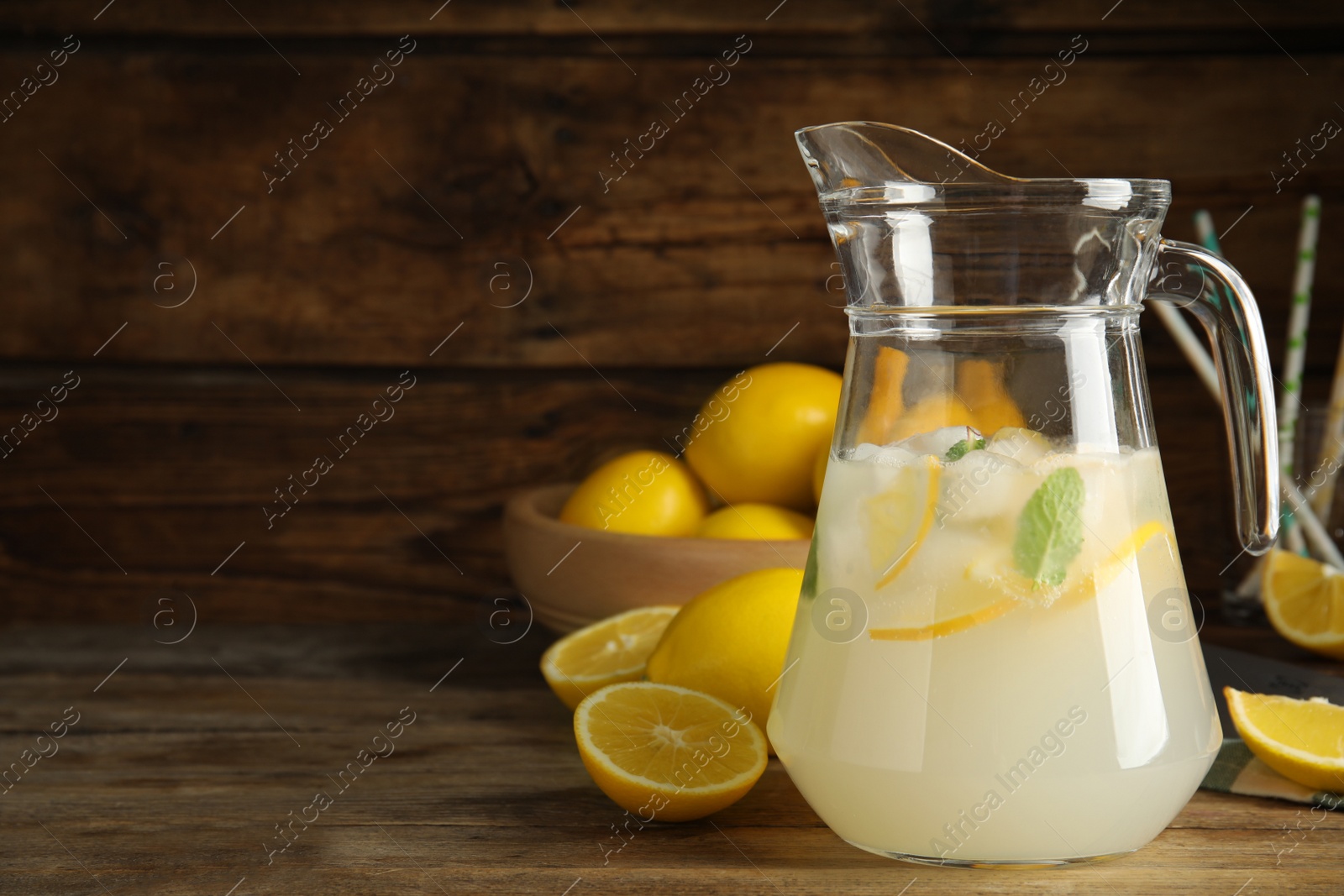 Photo of Cool freshly made lemonade in glass pitcher on wooden table. Space for text