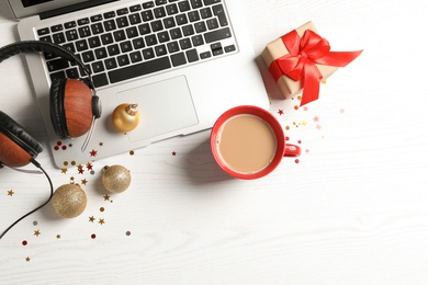 Flat lay composition with laptop, headphones and cup of coffee on wooden background. Christmas music concept