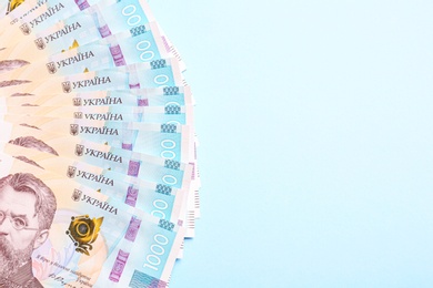 Photo of 1000 Ukrainian Hryvnia banknotes on light blue background, flat lay. Space for text