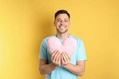 Photo of Portrait of man with decorative heart shaped pillow on color background