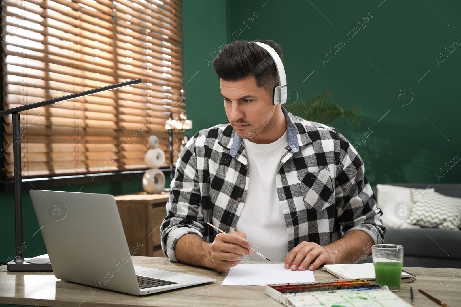 Photo of Man drawing with paints at online lesson indoors. Distance learning