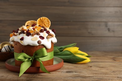 Tasty Easter cake with dried fruits, flowers and decorated eggs on wooden table. Space for text