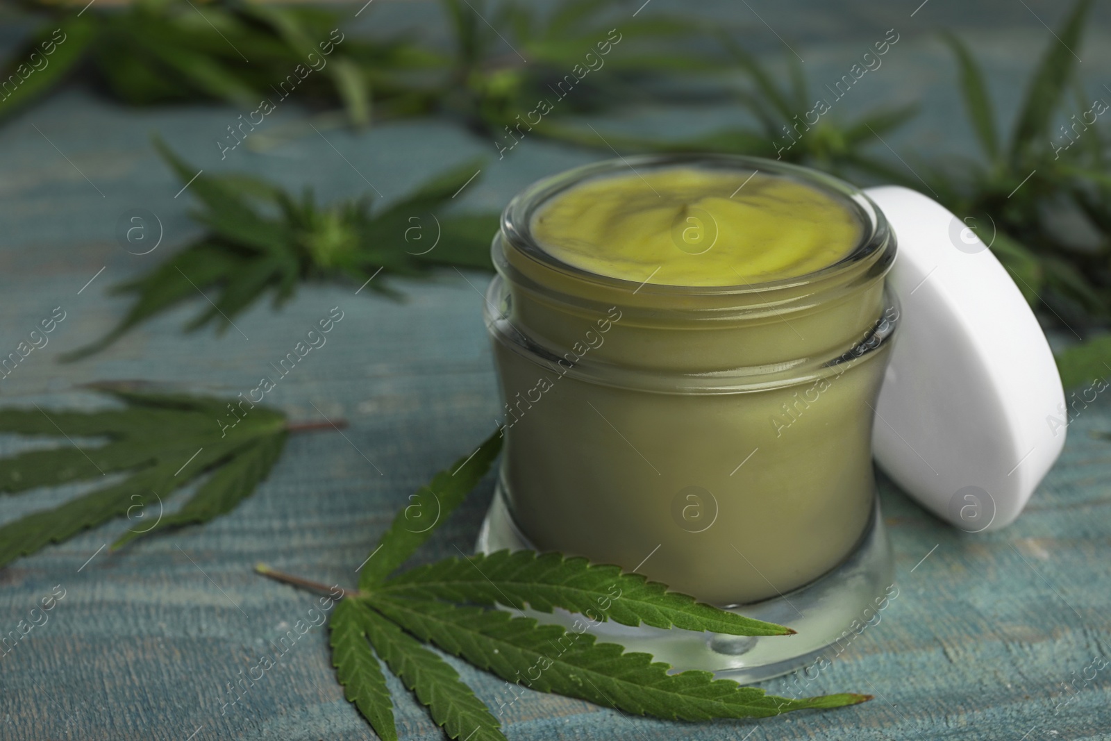 Photo of Jar of hemp cream on blue wooden table, space for text. Organic cosmetics