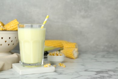 Photo of Tasty fresh corn milk in glass on white marble table. Space for text