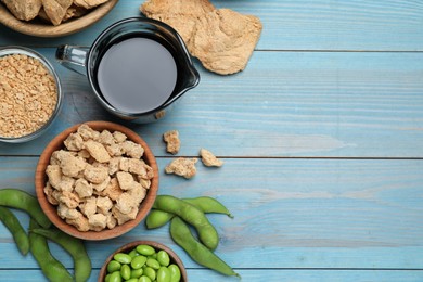 Different organic soy products on light blue wooden table, flat lay. Space for text