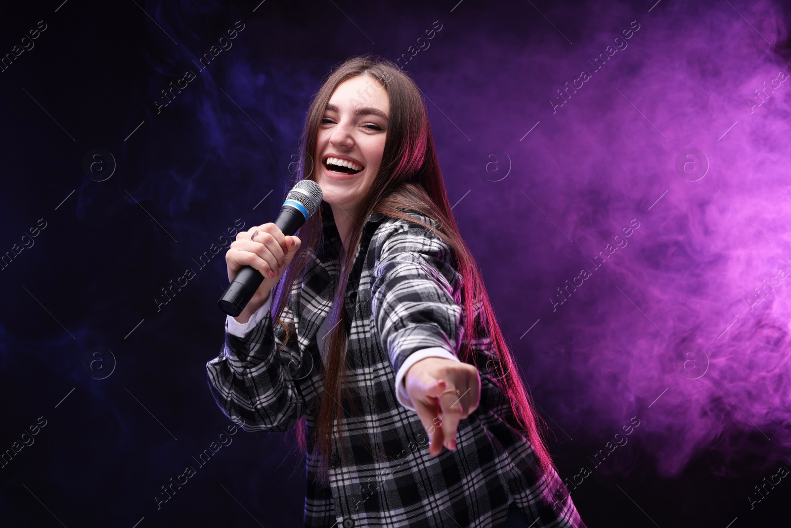 Photo of Emotional woman with microphone singing in color lights