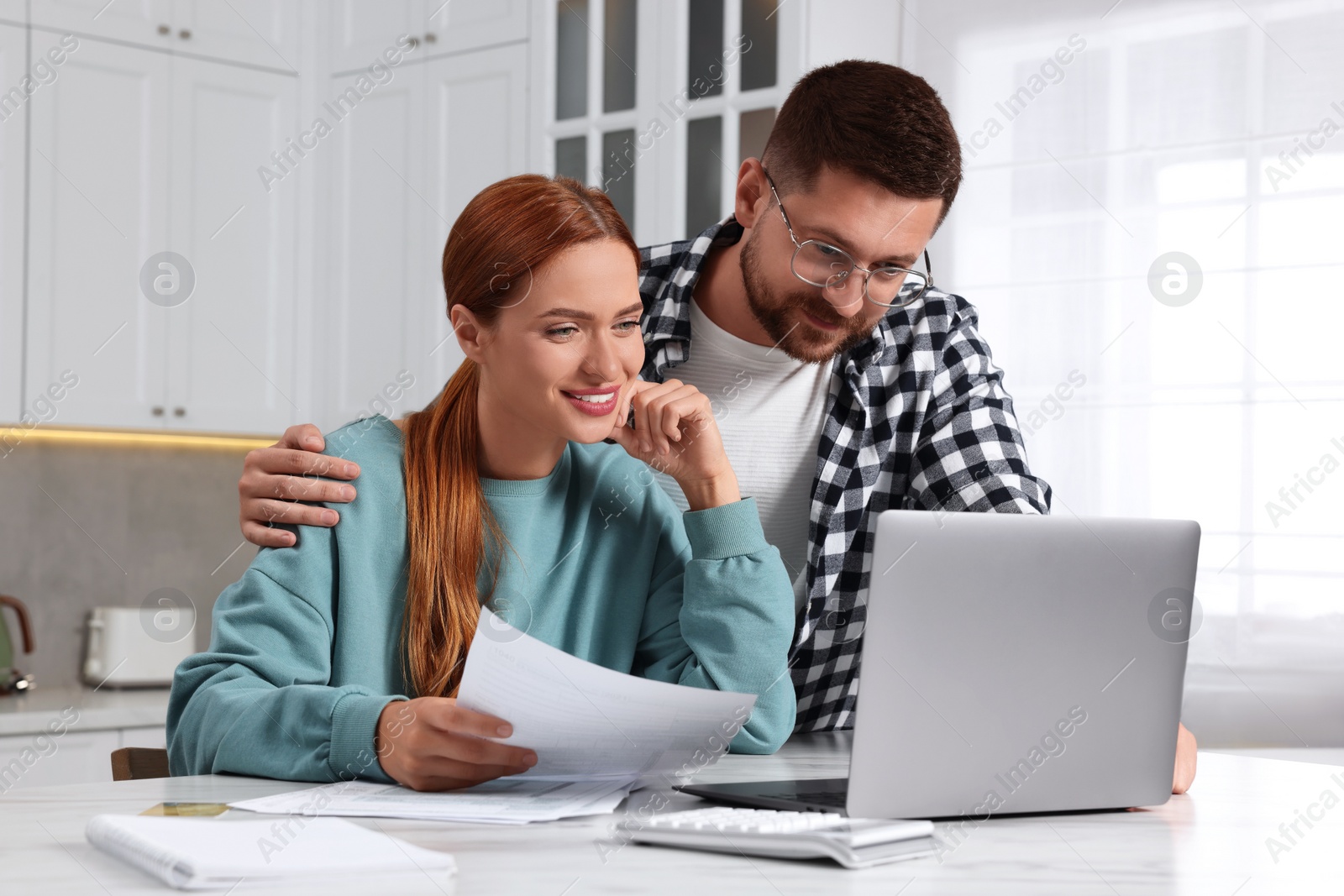 Photo of Couple using laptop for paying taxes at home