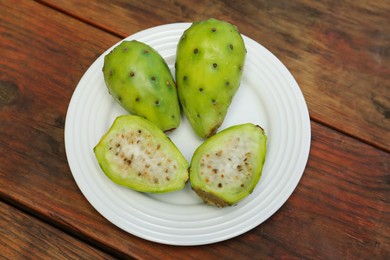 Photo of Tasty prickly pear cut and whole fruits on wooden table, top view