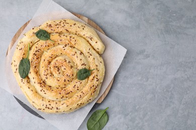 Photo of Delicious puff pastry with spinach on grey table, top view. Space for text