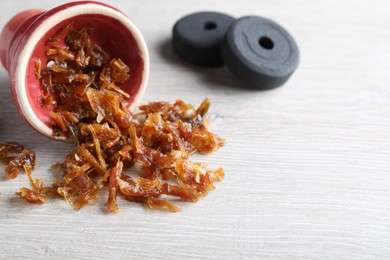 Red clay bowl of hookah with aromatic tobacco and charcoals on wooden table, closeup. Space for text