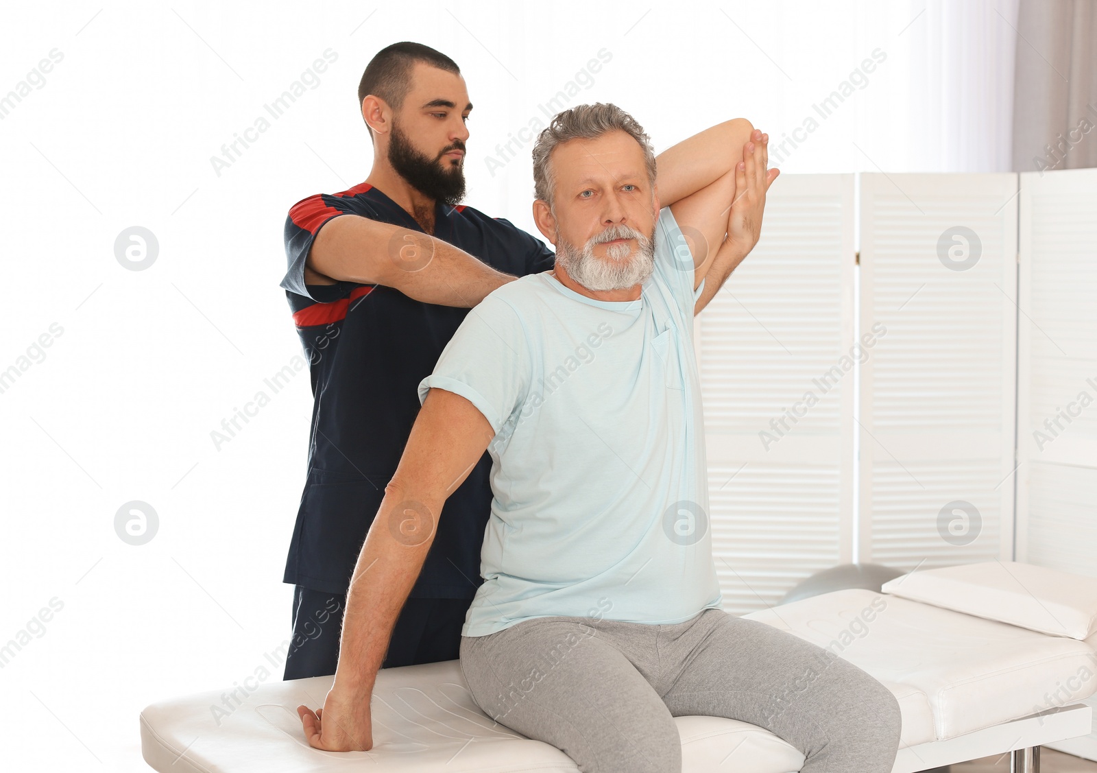 Photo of Physiotherapist working with patient in clinic. Rehabilitation therapy