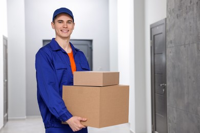 Photo of Young courier with cardboard boxes in hallway