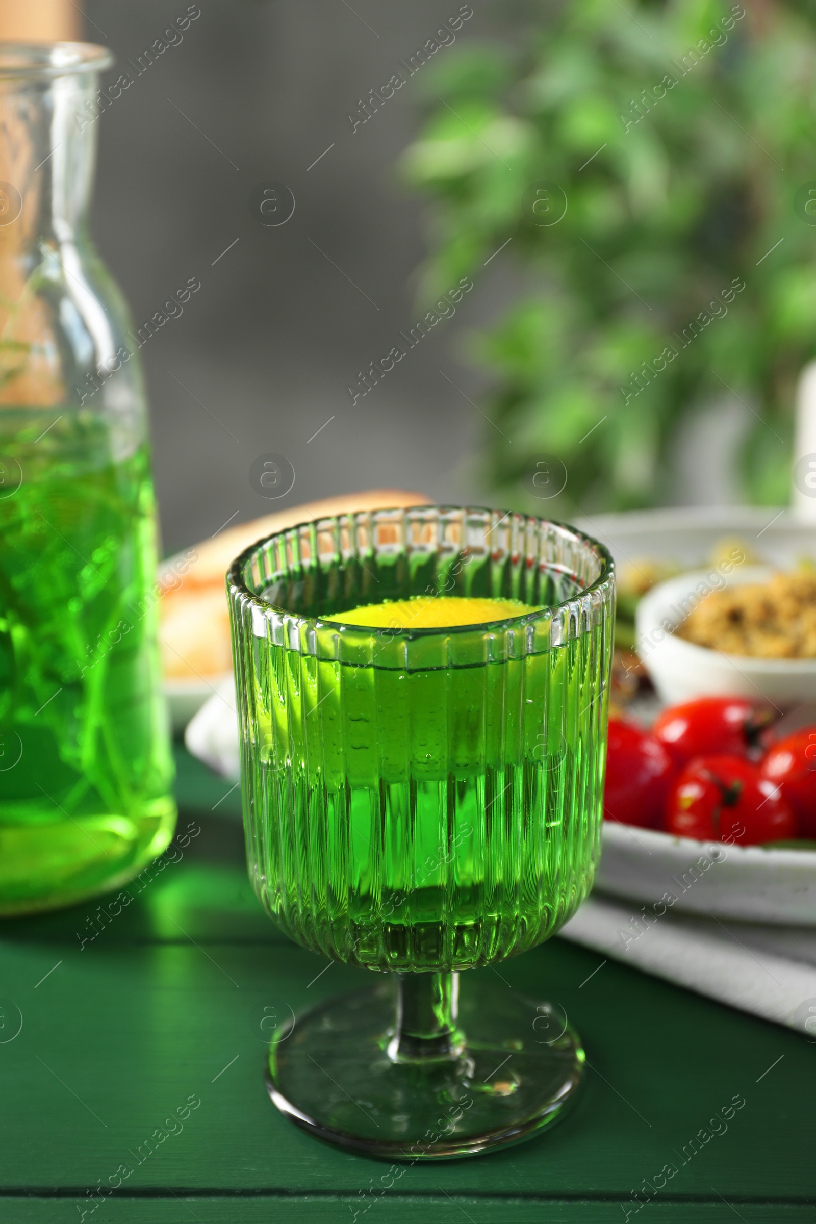 Photo of Delicious drink with tarragon in glass on green table. Space for text