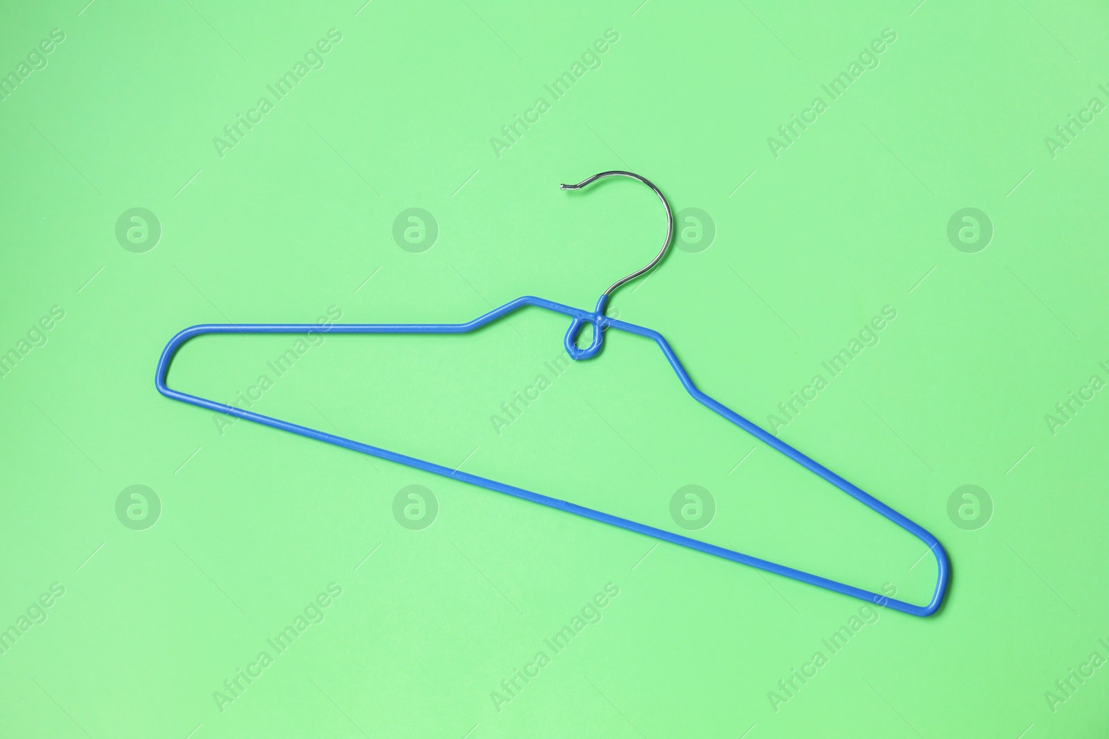 Photo of Empty blue hanger on light green background, top view
