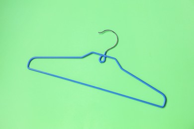 Photo of Empty blue hanger on light green background, top view