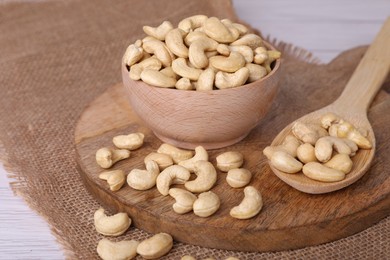 Photo of Tasty cashew nuts in bowl and spoon on table