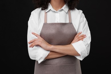 Woman wearing kitchen apron on black background, closeup. Mockup for design