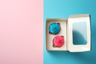 Box with different delicious cupcakes on color background, top view. Space for text