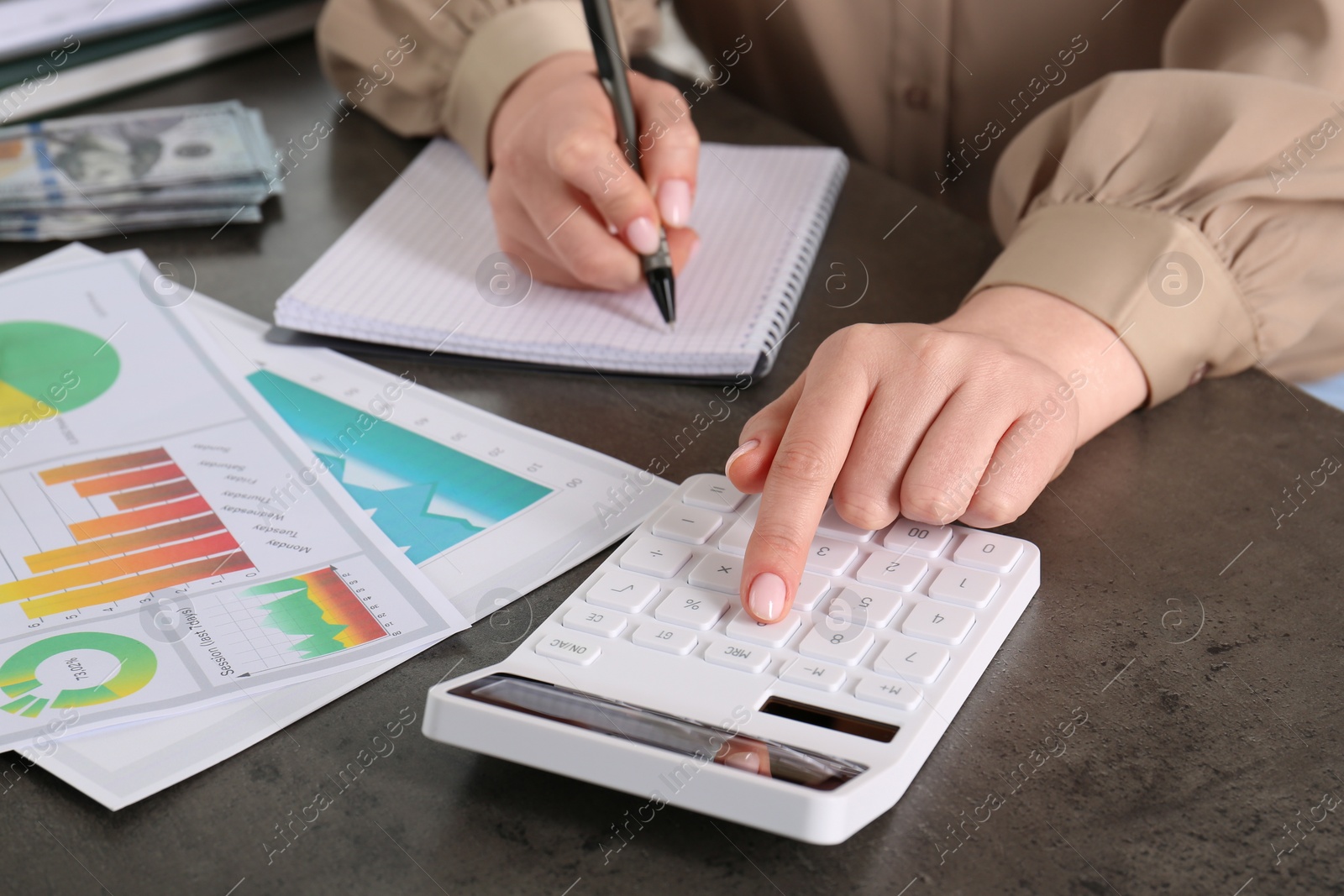 Photo of Woman calculating pension at grey table, closeup