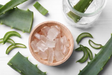 Photo of Aloe vera gel and slices of plant on white wooden table, flat lay