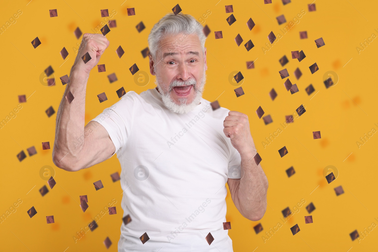 Image of Happy man under flying confetti on orange background