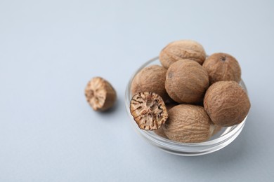 Photo of Nutmegs in glass bowl on white background. Space for text