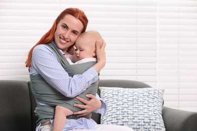 Mother holding her child in sling (baby carrier) indoors