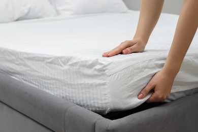 Photo of Woman putting new soft mattress on bed, closeup