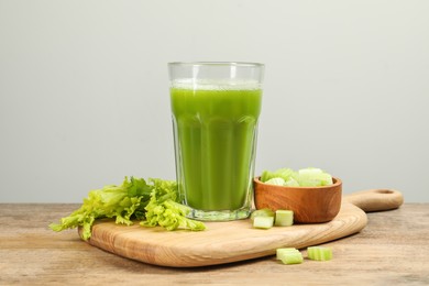 Photo of Glass of celery juice and fresh vegetables on wooden table