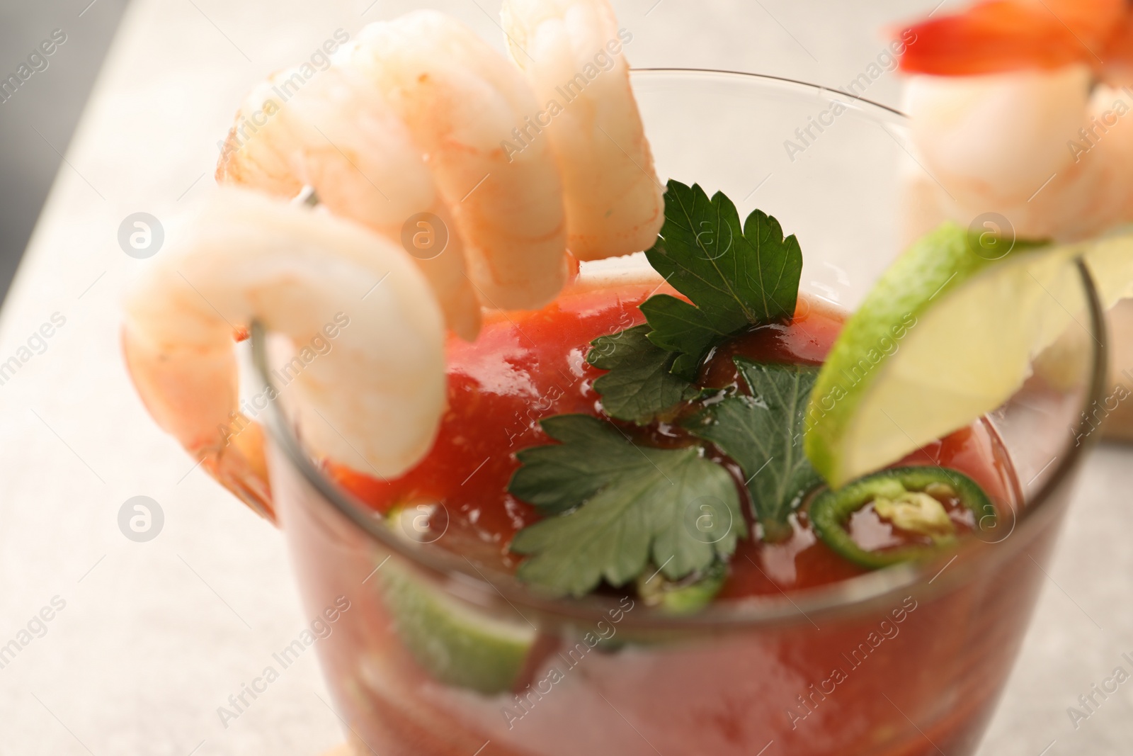 Photo of Tasty shrimp cocktail with sauce, parsley and lime in glass on table, closeup