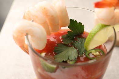 Photo of Tasty shrimp cocktail with sauce, parsley and lime in glass on table, closeup