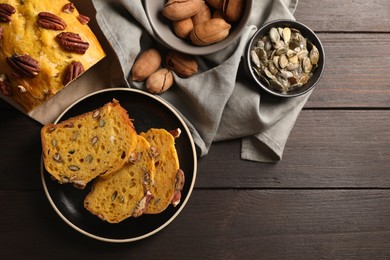 Delicious pumpkin bread with pecan nuts and seeds on wooden table, flat lay. Space for text