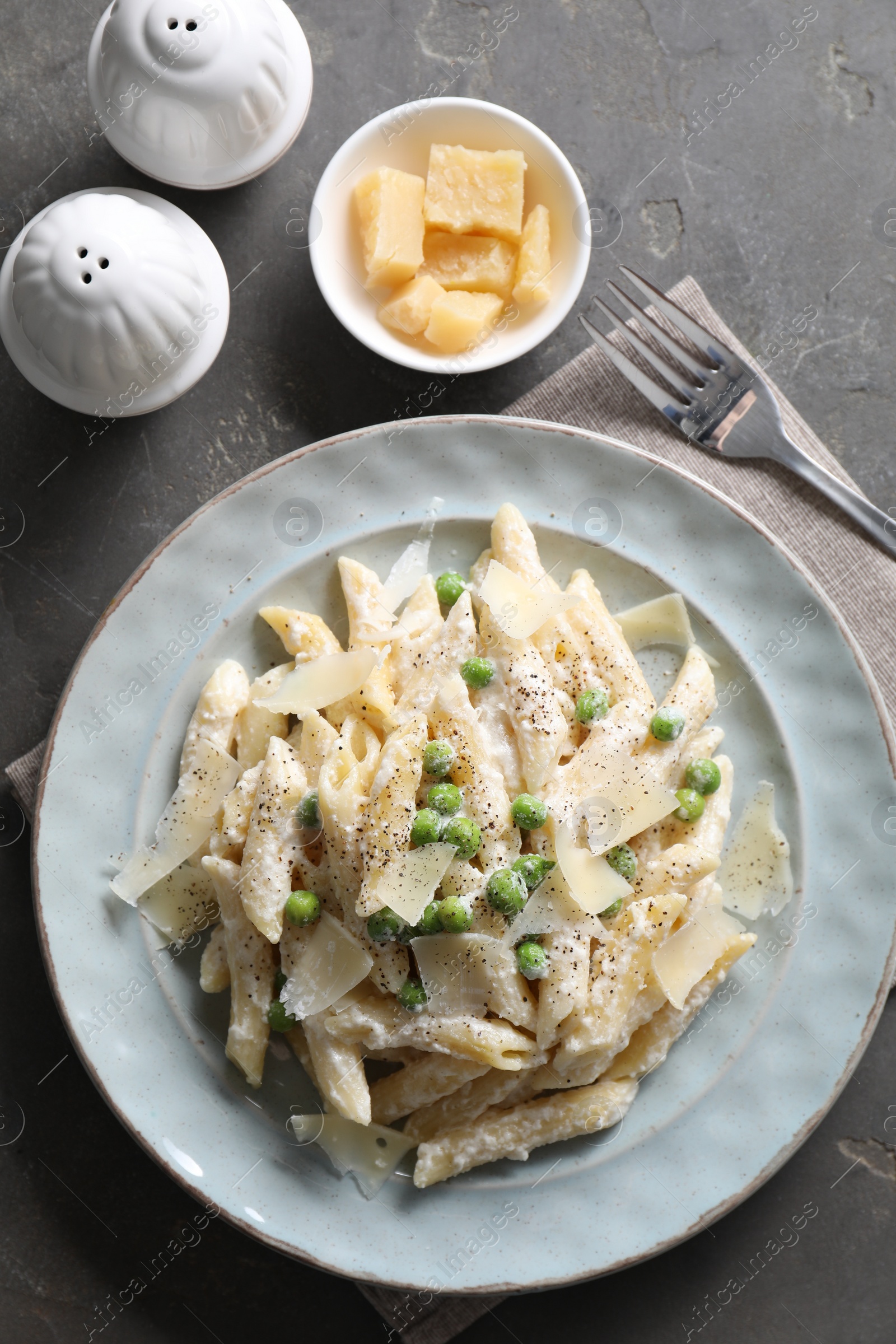 Photo of Delicious pasta with green peas, cheese and creamy sauce on grey table, top view